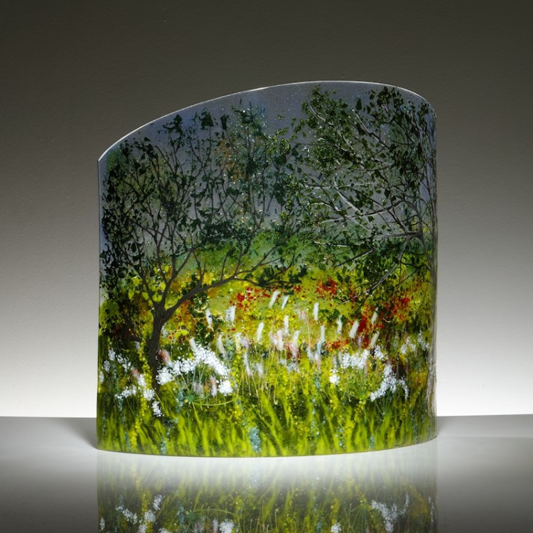 Curved glass sculpture featuring trees, spring flowers and bullrushes.