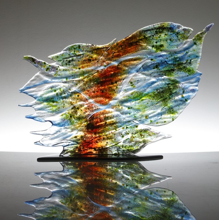 Glass sculpture in sections showing the patterns when sunlight in reflected on the water. Colours are reds, greens and blues. .