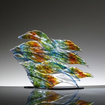 Fused glass sculpture on a black base. Colours reflected on the surface of the canal: blues, greens and reds.