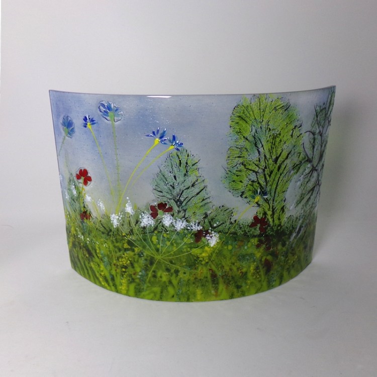Curved glass freestanding sculpture featuring cow parsley, poppies and cornflowers.