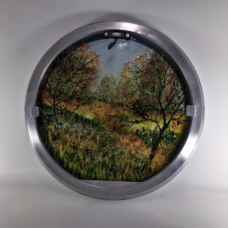 Boat porthole with glass showing tree with Autumn foliage.