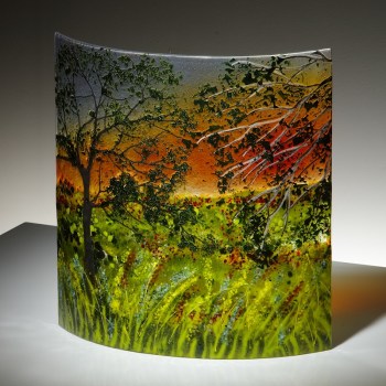 Curved glass sculpture showing a scene of a sunset through trees viewed from the towpath of the Chesterfield Canal.