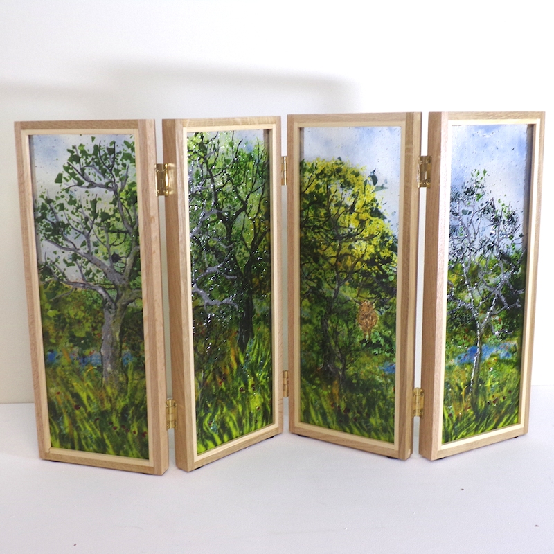 Table top screen. 4 glass panels framed in oak. Scene is of woodland with blue bells.