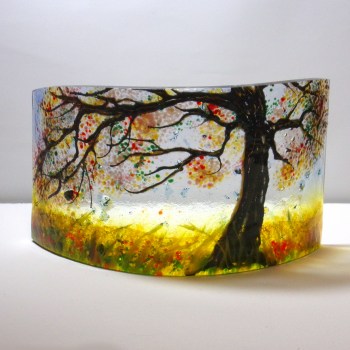 Curved glass sculpture without a base. Yellow, red and oranges colours to the leaves.