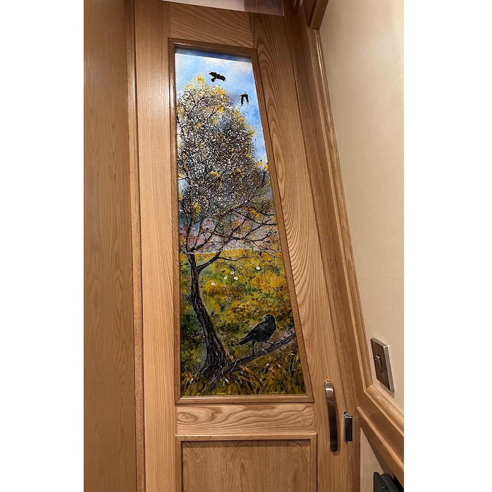 Fused glass interior door panel on a narrowboat. The design single tree with vivid coloured leaves and crows.