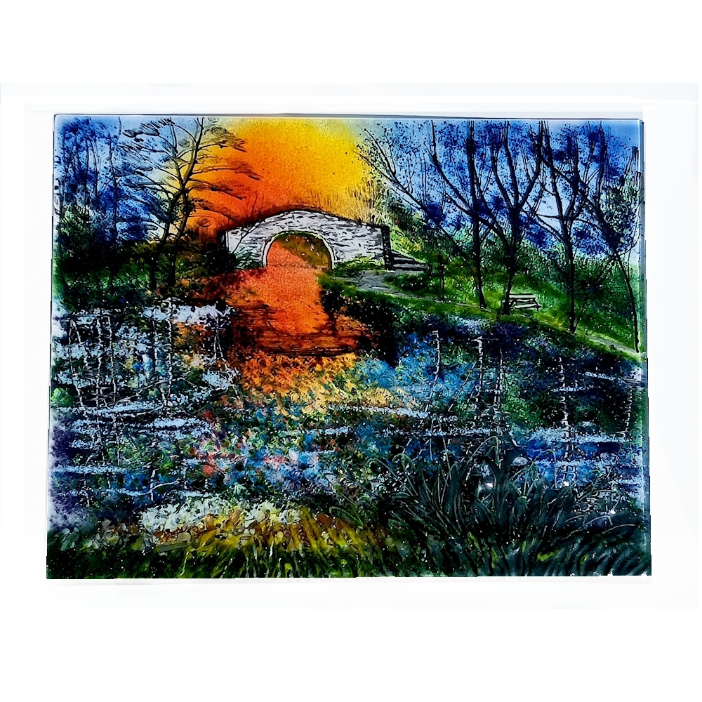 Humped back canal bridge with the sun setting behind.