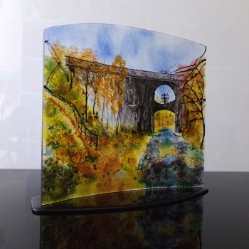 Curved glass sculpture with black glass base. Showing Bridge 39 on the canal in Autumn.