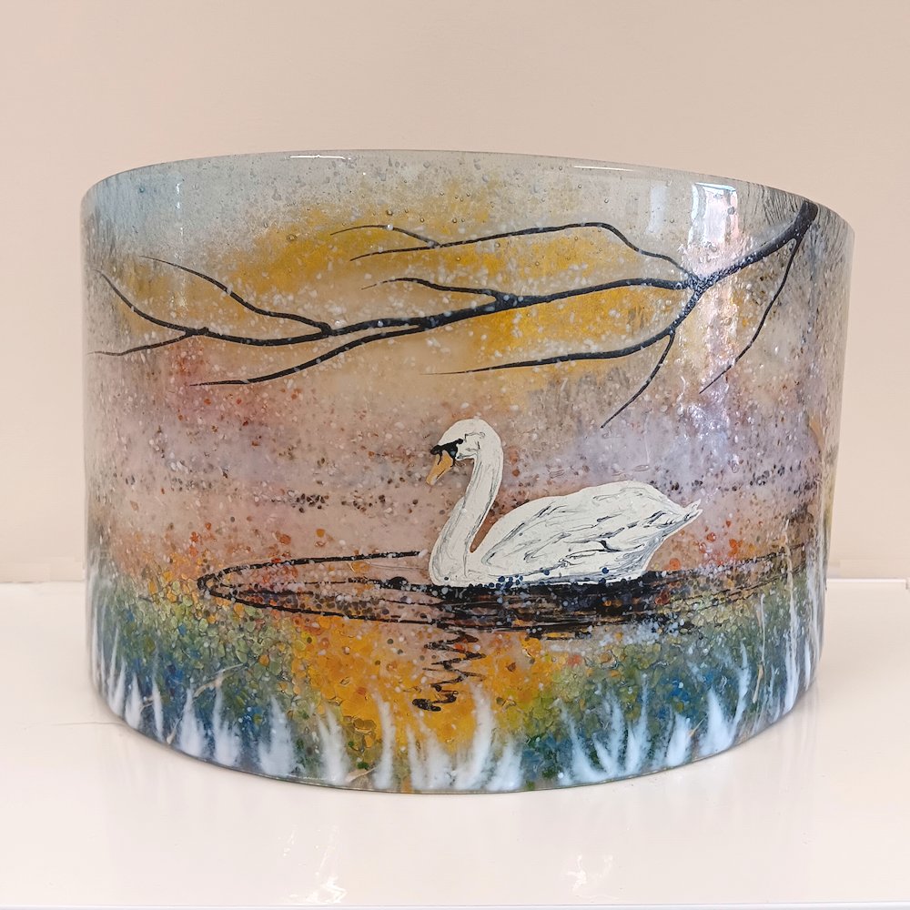Curved glass sculpture. Swans at dawn in a winter snow scene.