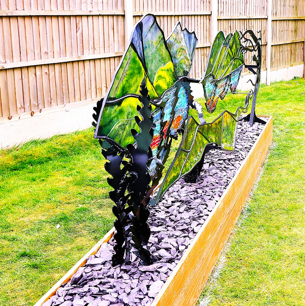 Garden Sculpture 'Kyles of Bute'. Black metal frame with coloured glass outlining the view of the loch.