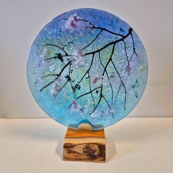 Glass disc sculpture on an oak stand, featuring cherry blossom against a bright blue spring sky.