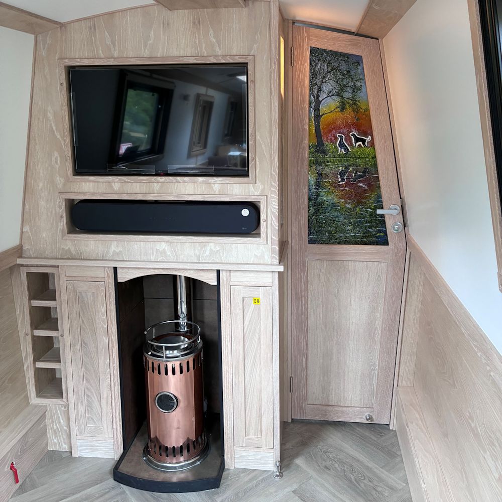 Photo inside of the boat 'Silver Ghost' showing a decorative glass door panel. The design is a sunset reflected in the canal with 2 Weimaraner dogs in silhouette.