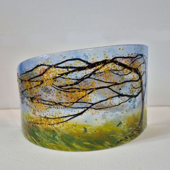 A windswept tree bowing in the force of an Autumn storm. Leaves in yellow/gold are blowing from the tree.