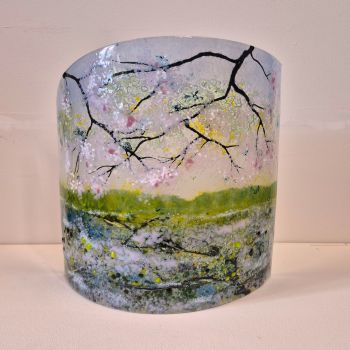 Fused curved fused glass sculpture. Branches of a Cherry Tree in blossom are reflected in the canal below.