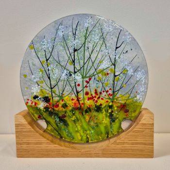 Glass disc sculpture on an oak stand, featuring cow parsley flowering .